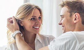  Casal loiro de olhos azuis sorrindo um para o outro. 