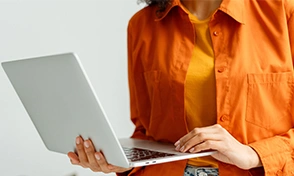  Mulher de blusa laranja segurando notebook 